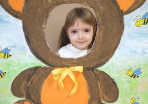 Dziecko pozuje do zdjęcia w ramce z misiem