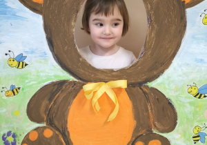 Dziecko pozuje do zdjęcia w ramce z misiem