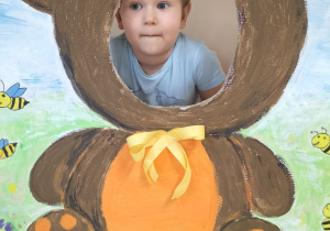 Dziecko pozuje do zdjęcia w ramce z misiem