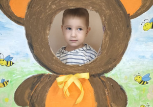 Dziecko pozuje do zdjęcia w ramce z misiem