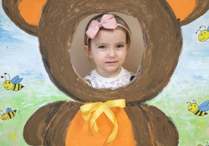 Dziecko pozuje do zdjęcia w ramce z misiem