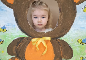 Dziecko pozuje do zdjęcia w ramce z misiem