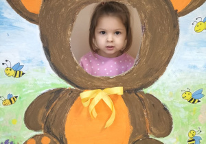 Dziecko pozuje do zdjęcia w ramce z misiem