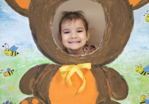 Dziecko pozuje do zdjęcia w ramce z misiem