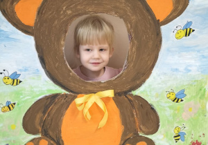 Dziecko pozuje do zdjęcia w ramce z misiem