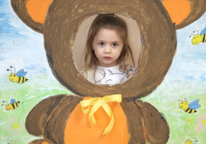 Dziecko pozuje do zdjęcia w ramce z misiem