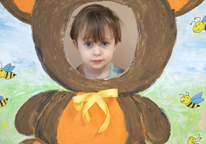 Dziecko pozuje do zdjęcia w ramce z misiem