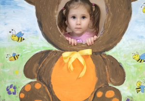 Dziecko pozuje do zdjęcia w ramce z misiem