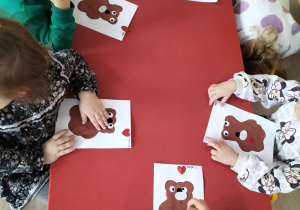 Dzieci wykonują pracę plastyczną z misiem