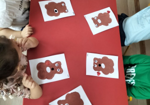 Dzieci wykonują pracę plastyczną z misiem