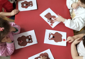 Dzieci wykonują pracę plastyczną z misiem