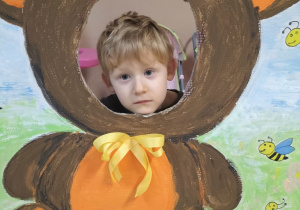 Dziecko pozuje do zdjęcia w ramce z misiem