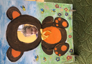 Dziecko pozuje do zdjęcia w ramce z misiem