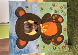 Dziecko pozuje do zdjęcia w ramce z misiem