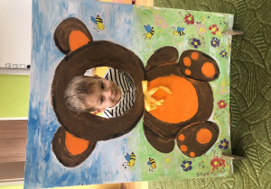 Dziecko pozuje do zdjęcia w ramce z misiem