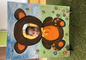 Dziecko pozuje do zdjęcia w ramce z misiem