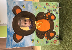 Dziecko pozuje do zdjęcia w ramce z misiem