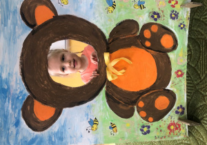 Dziecko pozuje do zdjęcia w ramce z misiem