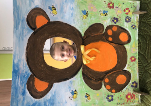 Dziecko pozuje do zdjęcia w ramce z misiem