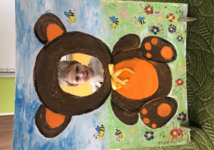 Dziecko pozuje do zdjęcia w ramce z misiem