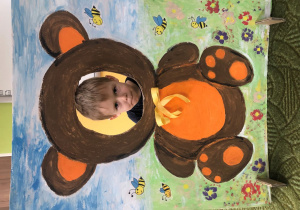 Dziecko pozuje do zdjęcia w ramce z misiem