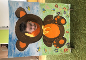 Dziecko pozuje do zdjęcia w ramce z misiem