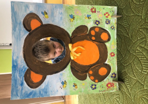 Dziecko pozuje do zdjęcia w ramce z misiem