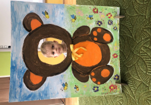 Dziecko pozuje do zdjęcia w ramce z misiem