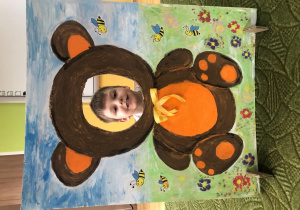 Dziecko pozuje do zdjęcia w ramce z misiem