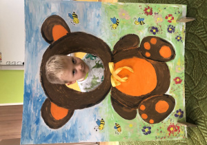 Dziecko pozuje do zdjęcia w ramce z misiem