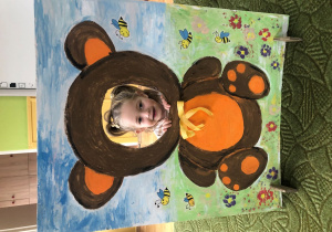 Dziecko pozuje do zdjęcia w ramce z misiem