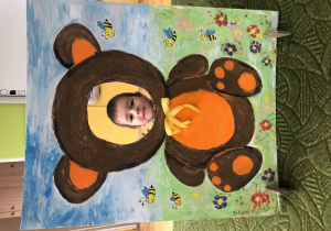 Dziecko pozuje do zdjęcia w ramce z misiem