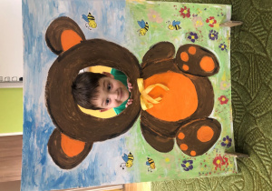 Dziecko pozuje do zdjęcia w ramce z misiem