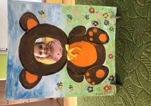 Dziecko pozuje do zdjęcia w ramce z misiem