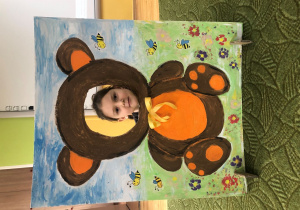 Dziecko pozuje do zdjęcia w ramce z misiem