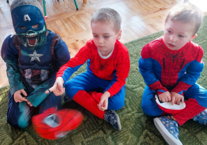 Dzieci siedzą na dywanie w sali przedszkolnej