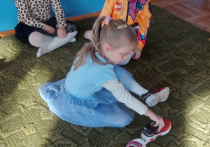 Dziewczynka układa but na dywanie