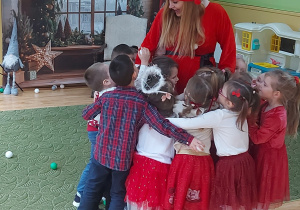 Dzieci przytulają się do Mikołajki prowadzącej bal świąteczny