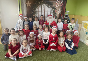 Dzieci pozują do zdjęcia z Mikołajem.