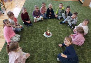 Dzieci siedzą w kole z Betlejemskim Światłem Pokoju