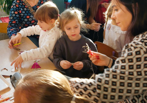 Rodzice z dziećmi wycinają z papieru elementy łańcucha choinkowego