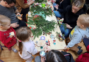 Rodzice z dziećmi tworzą świąteczne stroiki