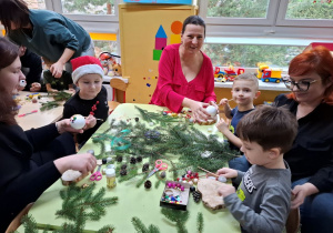 Rodzice z dziećmi tworzą świąteczne stroiki