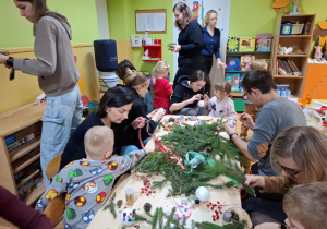 Rodzice z dziećmi tworzą świąteczne stroiki