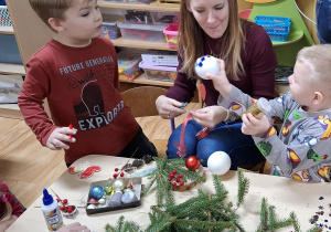 Rodzice z dziećmi tworzą świąteczne stroiki