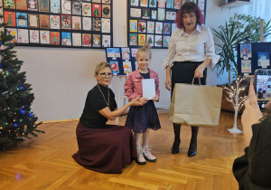 Dziewczynka odbiera dyplom oraz nagrodę.
