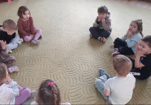 Dzieci siedzą w kole na dywanie