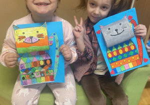 Dziewczynki prezentują wykonaną pracę kotów z papieru