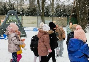 Dzieci bawią się śniegiem w ogrodzie przedszkolnym