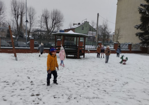 Dzieci bawią się śniegiem w ogrodzie przedszkolnym
